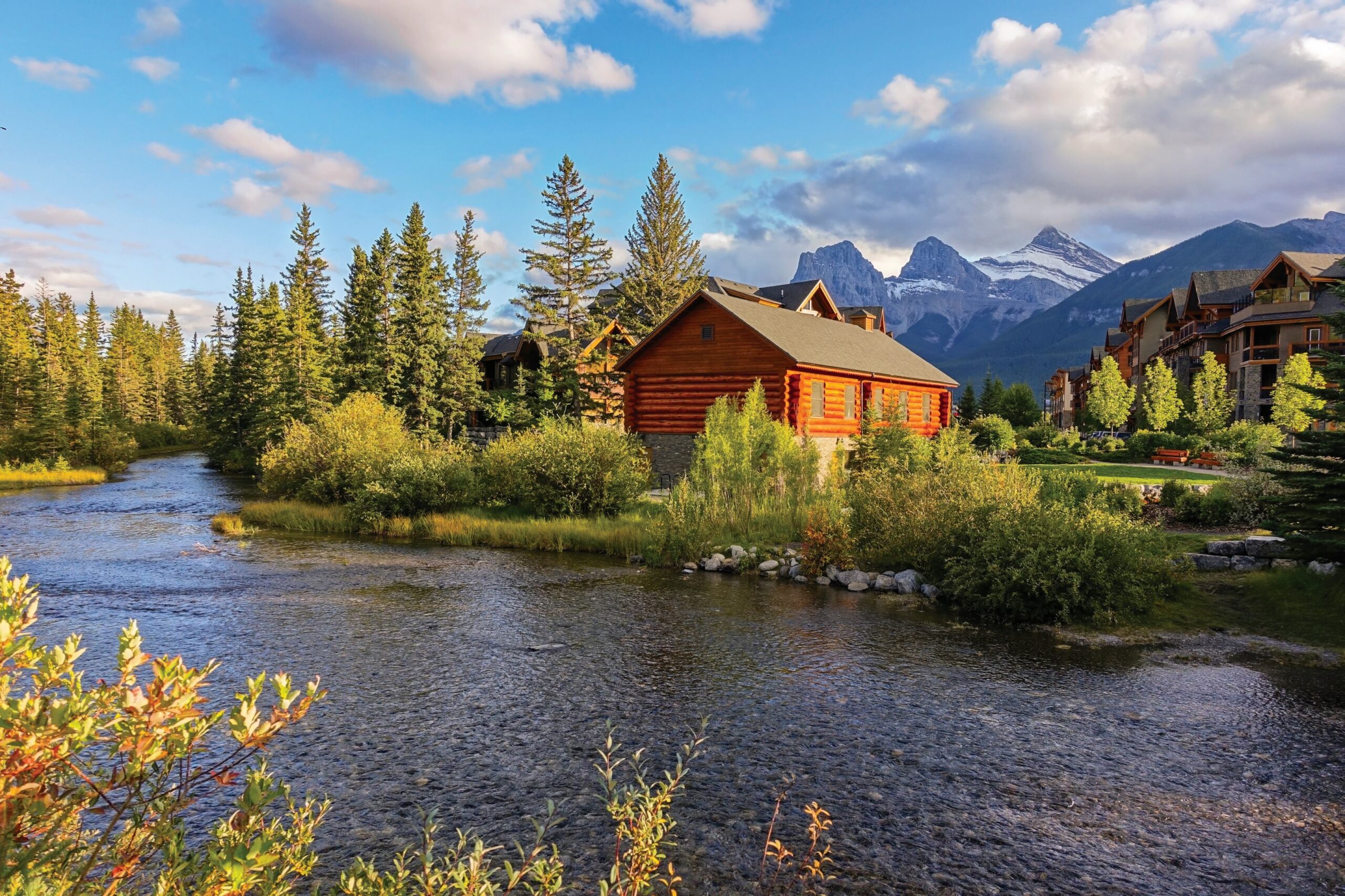 beautiful cabin near a river with mountains in the background